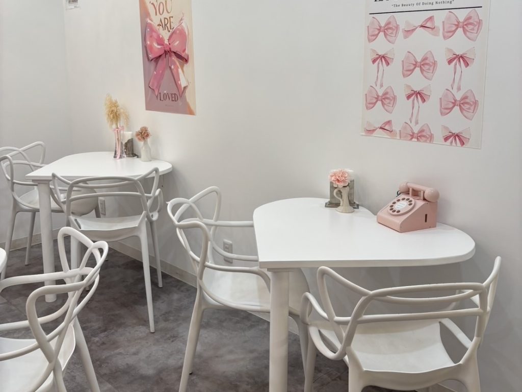 Cafe Ksyn'n(カフェ・カシノン)の壁を向くように配置されたオーダーメイドのハート型テーブル席と、卓上に置かれたピンクの小物